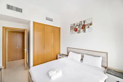 a bedroom with a white bed and a wooden door at StoneTree - Furnished 1BR with Canal View in Dubai