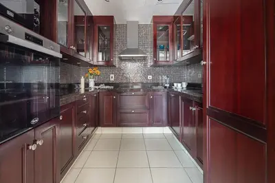 a large kitchen with red cabinets and white tile floors at Frank Porter - Reehan 1 in Dubai