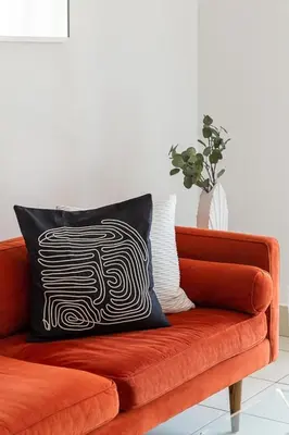 a orange couch with a black and white pillow on it at Frank Porter - Reehan 1 in Dubai