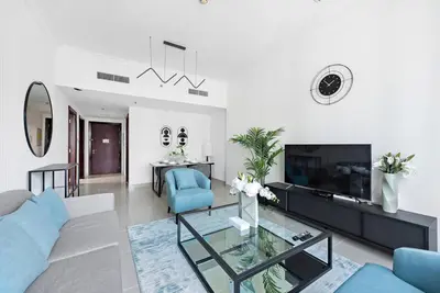 a living room with a blue couch and a tv at StoneTree - NEW Furnished 1BR in V3 Tower in Dubai