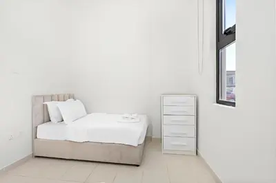 a white bedroom with a bed and a dresser at StoneTree - The Modern Family Friendly Villa in Dubai