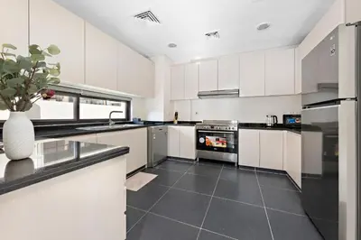 a kitchen with white cabinets and a vase with a plant at StoneTree - The Modern Family Friendly Villa in Dubai