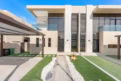 a child sitting on the grass in front of a house at StoneTree - The Modern Family Friendly Villa in Dubai