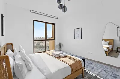 a white bedroom with a bed and a window at StoneTree - Elegant 1 BR in Madinat Jumeirah Living Rahaal 2 in Dubai