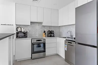 a white kitchen with white cabinets and appliances at StoneTree - Elegant 1 BR in Madinat Jumeirah Living Rahaal 2 in Dubai