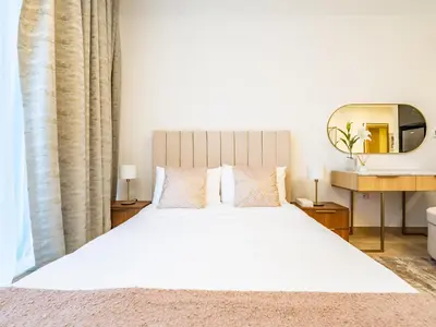 a bedroom with a large white bed with a mirror at Comfy and stylish Studio in Regina Towers - JVC in Dubai