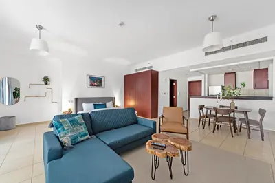 a living room with a blue couch and a table at Sleek Studio in JBR with Pool & Dubai Skyline View in Dubai