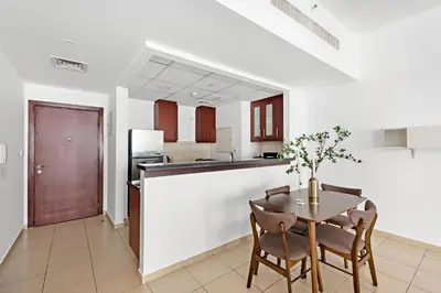 a kitchen and dining room with a table and chairs at Sleek Studio in JBR with Pool & Dubai Skyline View in Dubai