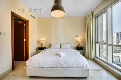 a bedroom with a white bed with two windows at Fairways Tower by Emaar, The Views and Greens in Dubai
