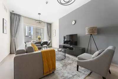 a living room with a couch and chairs and a tv at StoneTree - Furnished 1BR with Modern Design in Dubai