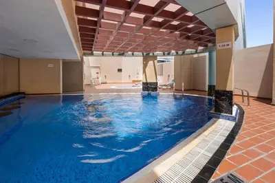 a large swimming pool with blue water in a building at StoneTree - Furnished 1BR with Modern Design in Dubai