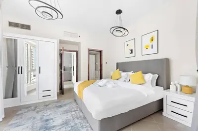 a bedroom with a large white bed with yellow pillows at StoneTree - Furnished 1BR with Modern Design in Dubai