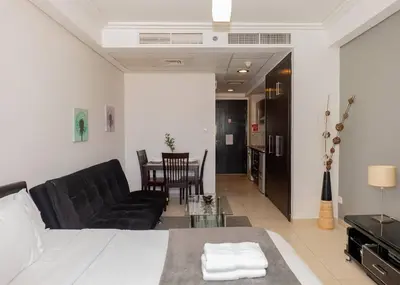 a living room with a bed and a couch and a table at StoneTree - Family-friendly Studio in Peaceful Community in Dubai