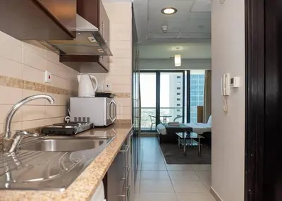 a kitchen with a sink and a living room at StoneTree - Family-friendly Studio in Peaceful Community in Dubai