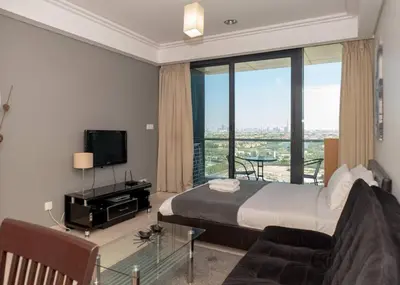 a bedroom with a bed and a tv and a couch at StoneTree - Family-friendly Studio in Peaceful Community in Dubai