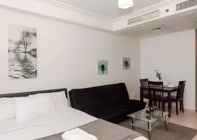 a living room with a bed and a table at StoneTree - Family-friendly Studio in Peaceful Community in Dubai