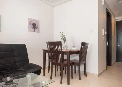 a living room with a dining room table and chairs at StoneTree - Family-friendly Studio in Peaceful Community in Dubai