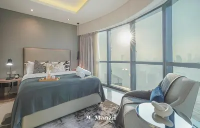a bedroom with a king sized bed and a chair at Manzil - Stunning 3BR Apt in Paramount nr Burj in Dubai