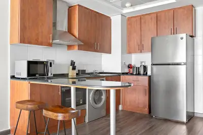 a kitchen with a stainless steel refrigerator and wooden cabinets at StoneTree - Amazing 1BR with Lake View in Dubai