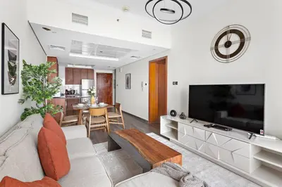 a living room with a couch and a tv at StoneTree - Amazing 1BR with Lake View in Dubai