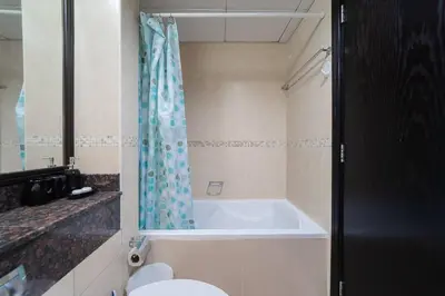 a bathroom with a bath tub and a toilet at StoneTree - Fully Furnished Studio with Spacious Balcony in Dubai