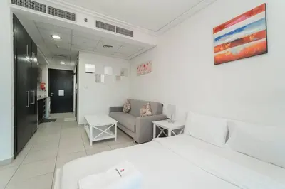 a white bedroom with a bed and a couch at StoneTree - Fully Furnished Studio with Spacious Balcony in Dubai