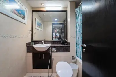 a bathroom with a sink and a toilet and a mirror at StoneTree - Fully Furnished Studio with Spacious Balcony in Dubai