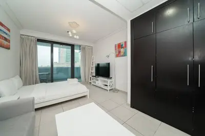 a living room with a couch and a television at StoneTree - Fully Furnished Studio with Spacious Balcony in Dubai