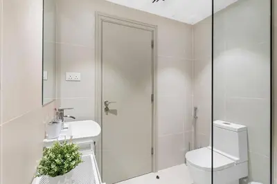 a white bathroom with a toilet and a sink at Cozy Studio By Burj Khalifa and Dubai Mall in Dubai