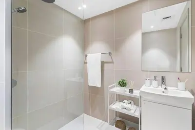 a white bathroom with a shower and a sink at Cozy Studio By Burj Khalifa and Dubai Mall in Dubai