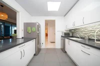 a kitchen with white cabinets and a stainless steel refrigerator at StoneTree - Spacious 2BR in Great Location in Dubai