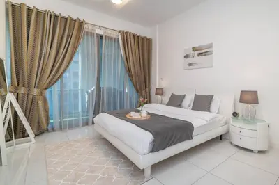 a bedroom with a bed and a large window at StoneTree - Spacious 2BR in Great Location in Dubai