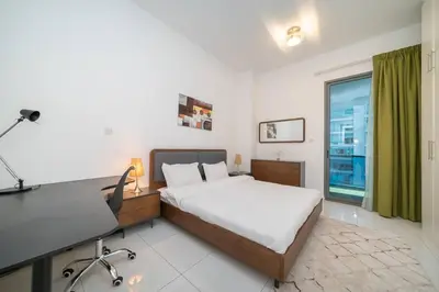 a bedroom with a bed and a desk and a window at StoneTree - Spacious 2BR in Great Location in Dubai