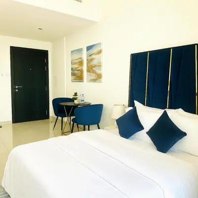 a bedroom with a large bed with blue pillows and a table at Stylish Studio For Two in Dubai
