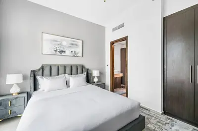 a bedroom with a white bed and a wooden cabinet at StoneTree - Elegant 1BR with Amazing Building Facilities in Dubai