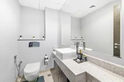 a white bathroom with a toilet and a sink at StoneTree - Elegant 1BR with Amazing Building Facilities in Dubai