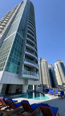 a tall building with chairs and a swimming pool at Marina Panorama Paradise in Dubai
