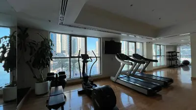 a gym with exercise equipment in a large room with windows at Marina Panorama Paradise in Dubai