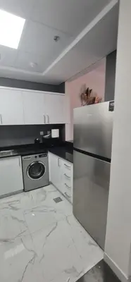 a kitchen with white marble floors and a refrigerator at Dar Alsalam - Spacious and Bright 1BR Apartment in Majan in Dubai
