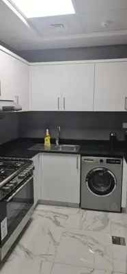 a kitchen with a sink and a washing machine at Dar Alsalam - Spacious and Bright 1BR Apartment in Majan in Dubai