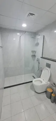 a bathroom with a toilet and a glass shower at Dar Alsalam - Spacious and Bright 1BR Apartment in Majan in Dubai