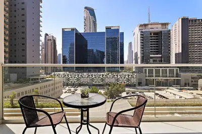 a table and chairs on a balcony with a view of a city at StoneTree - Modern 1BR Apartment in Vera Residence in Dubai