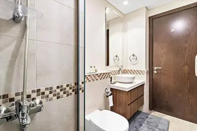 a bathroom with a toilet and a sink and a shower at StoneTree - Modern 1BR Apartment in Vera Residence in Dubai