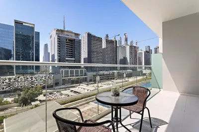 a balcony with a table and chairs and a view of a city at StoneTree - Modern 1BR Apartment in Vera Residence in Dubai