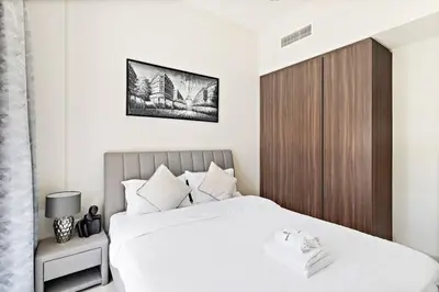 a bedroom with a large bed with a wooden headboard at StoneTree - Modern 1BR Apartment in Vera Residence in Dubai