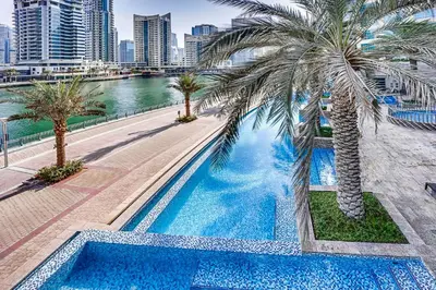 a swimming pool with palm trees next to a river at StoneTree - Stylish fully-furnished 1 BR in Dubai