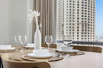 a dining table with glasses and a vase with a flower at StoneTree - Stylish fully-furnished 1 BR in Dubai