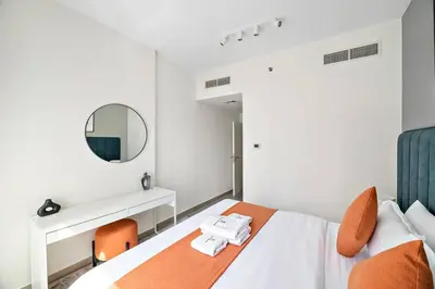 a bedroom with a bed with orange chairs and a mirror at StoneTree - Furnished 1BR with Stunning View in Dubai
