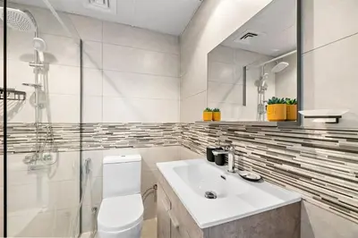 a white bathroom with a sink and a shower at StoneTree - Furnished 1BR with Stunning View in Dubai