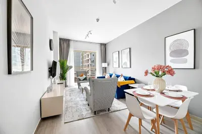 a white living room with a table and chairs at StoneTree - Furnished 1BR with Stunning View in Dubai